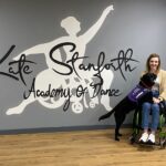 Kate Stanforth Academy of Dance written in stylish lettering with Kate on the right sat in her wheelchair in a dance studio