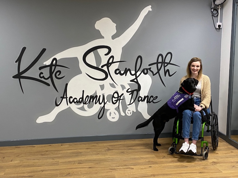 Kate Stanforth Academy of Dance written in stylish lettering with Kate on the right sat in her wheelchair in a dance studio