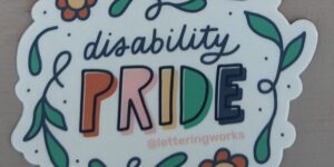 'Disability pride' sticker with pride in capital letters and the words surrounded by flowers