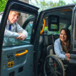 Amy Conachan as Courtney in Hollyoaks sat in her wheelchair in a black cab
