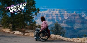 An everyday athlete picture showing a wheelchair users on a path with mountains in the background.