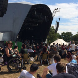 A woman in a Mountain Trike all-terrain wheelchair at a festival in front of a stage