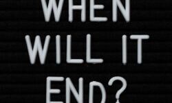 Blackboard with white letters spelling out the words when will it end