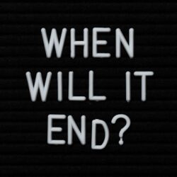 Blackboard with white letters spelling out the words when will it end