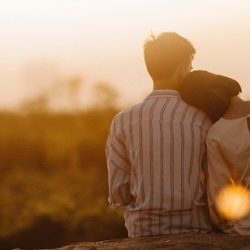 Couple sat in front of a sunset