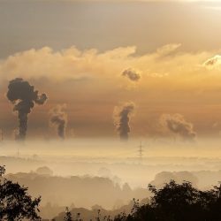 Smoke from factories and electricity pylons against a sunset