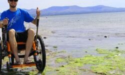 Tim Morgan in his Mountain Trike all-terrain wheelchair on a rocky beach