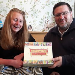 woman iwth long hair and a man with glasses and a beard hold a board game