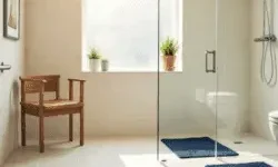 Accessible bathroom with grab bars, a walk-in shower with handheld showerhead, non-slip navy mats, a wooden shower chair, and a raised toilet.