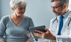 Doctor shows an older woman something on a tablet during a consultation in a medical office