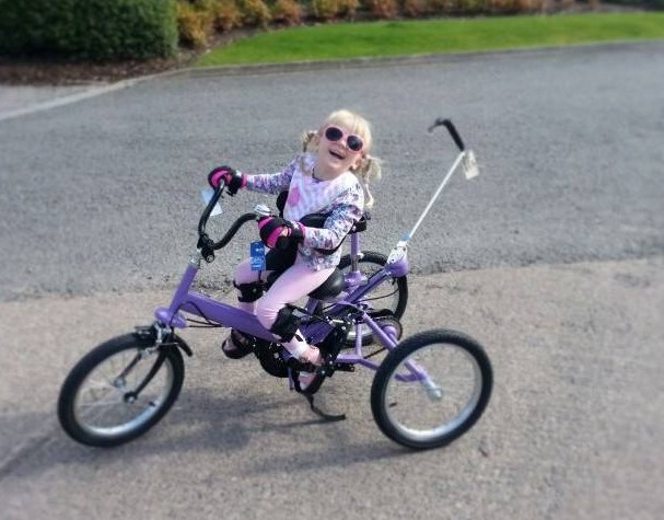 Girl holding onto Tomcat trike with general purpose gripping aids