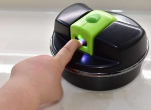 A child's hand is shown with their index finger in the opening of the Clip Different electric nail clipper.
