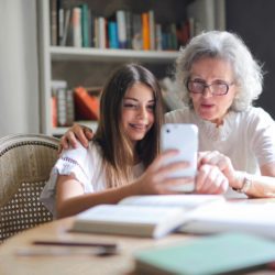 older woman showing something on her phone to younger girl (grand daughter?)