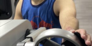 image shows rob using a hand cycle, holding the handle using a Hook Aid
