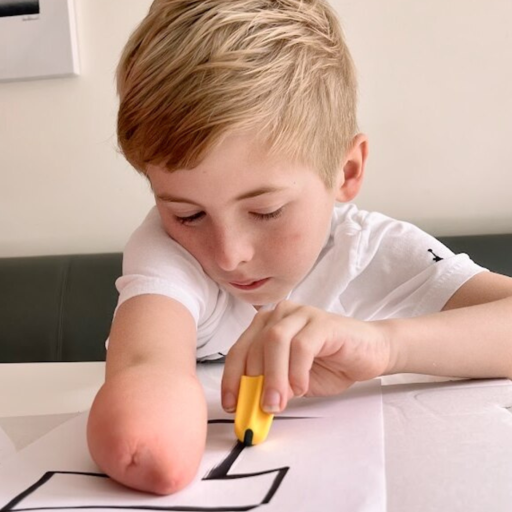 Tommy, who has an upper limb difference, uses the Nimble to cut some paper.